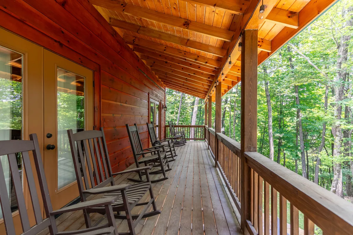 Rocking chairs line a wooden porch overlooking lush greenery, providing a tranquil spot for guests to soak in the peaceful mountain surroundings. The setting encourages moments of reflection after a day spent browsing shops and sampling local cuisine.