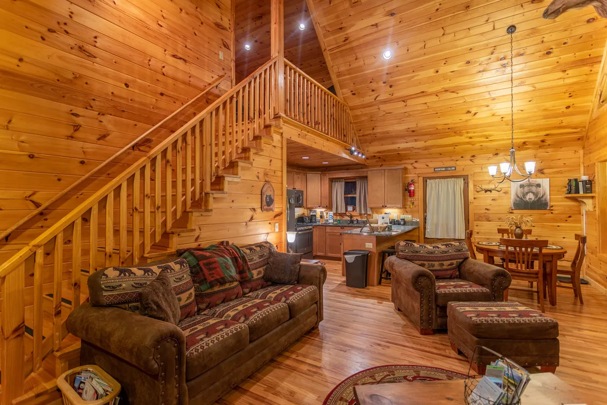 This open-concept interior view shows the kitchen area adjoining a dining table set for four. The scene also captures a wooden staircase and a comfortable seating area, underscoring the warm, communal feel of the space where meals and memories are made.